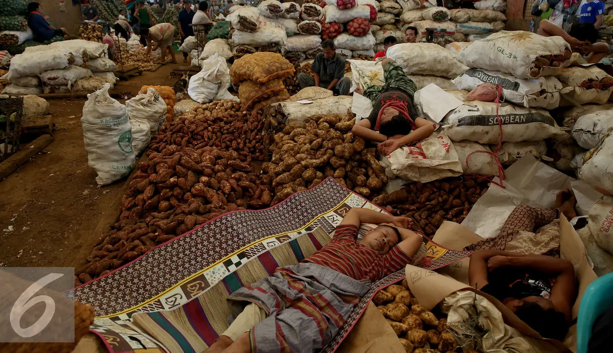 Buruh angkut tertidur diantara sayur mayur dagangan di kawasan Pasar Induk Kramat Jati, Jakarta, Sabtu (14/01). Sempitnya lapangan pekerjaan dan pendidikan yang minim membuat mereka nekat untuk mengadu nasib sebagai buruh angkut. (Liputan6.com/JohanTallo)