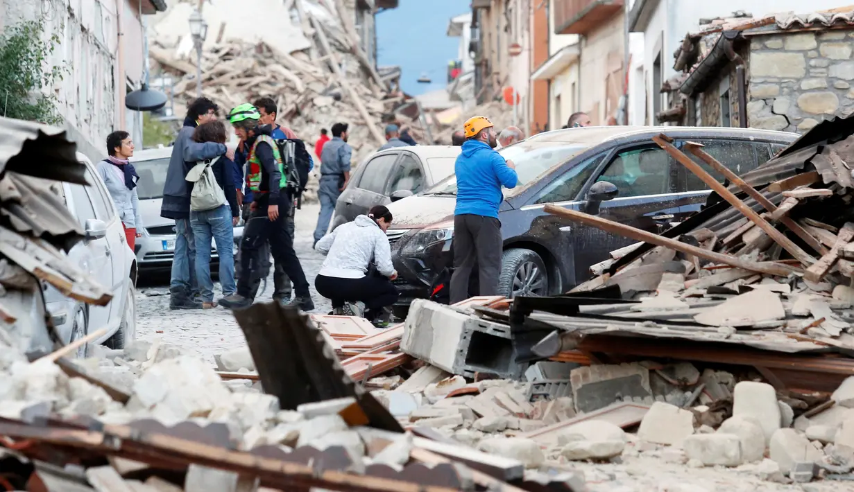 Sejumlah orang mengamati puing-puing bangunan yang rusak setelah gempa 6,2 SR di Amatrice, Italia tengah, Kamis (24/8). Gempa kuat tersebut menyebabkan bangunan runtuh, korban berjatuhan dan memicu kepanikan warga. (REUTERS/Remo Casilli)