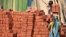 Seorang anak membantu ibunya mengangkat batu batu di sebuah bangunan New Delhi, India, Minggu (19/11). Sebagian dari mereka ada yang dipaksa ataupun terpaksa untuk membantu memenuhi kebutuhan hidup keluarganya. (DOMINIQUE FAGET)