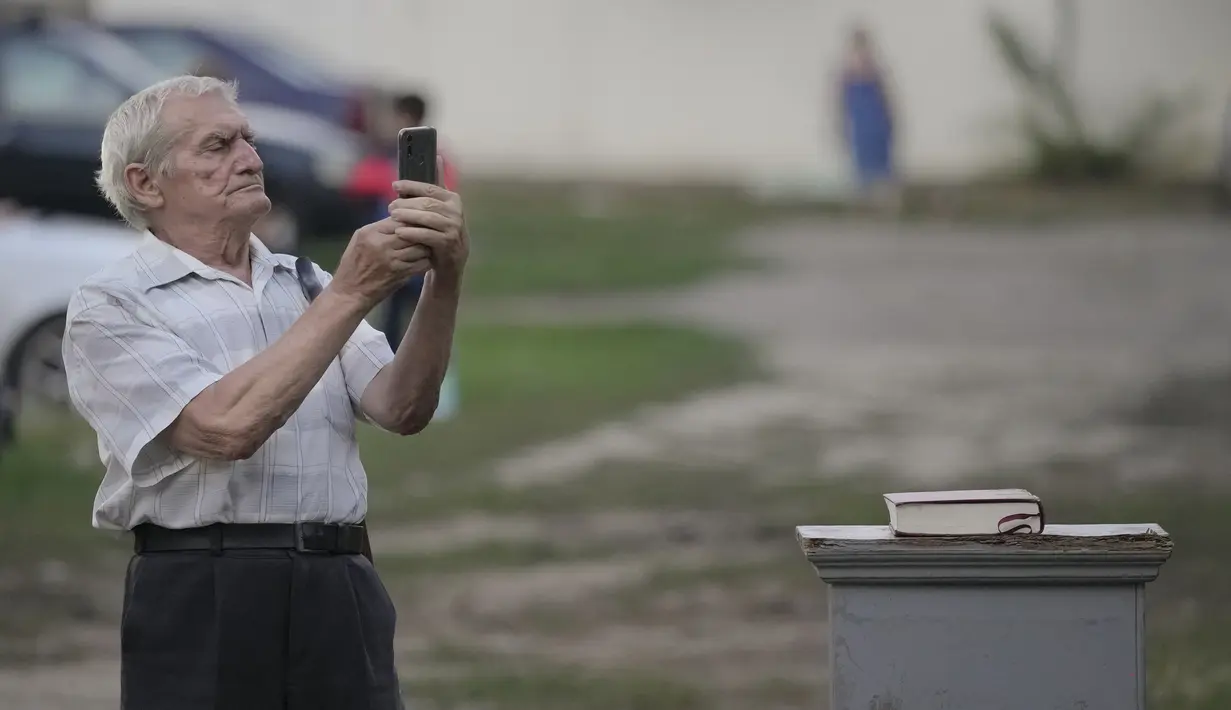 Seorang pria mengambil gambar selama pemutaran sejumlah film bertema kekerasan aparat, dalam sebuah festival 'outdoor' di Bucharest, Rumania (31/8/2021). Film-film yang ditampilkan di festival ini berisi pesan keragaman budaya, anti diskriminasi ras, dan kesenjangan sosial. (AP Photo/ Vadim Ghirda)