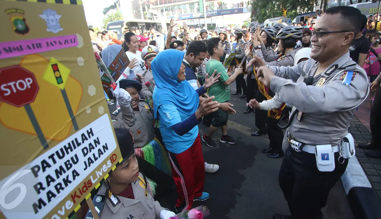 Petugas kepolisian bersama polisi cilik berjoged saat melakukan kampanye keselamatan berkendara di kawasan Bundaran HI, Jakarta, Minggu (12/3). (Liputan6.com/Immanuel Antonius)