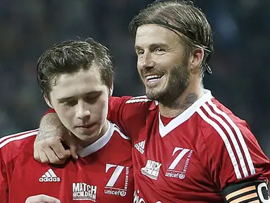 Pesepakbola David Beckham memeluk anaknya Brooklyn ketika mereka sedang bertanding bola dalam laga amal di Old Trafford, Inggris, Sabtu (14/11/2015). Dalam laga amal bertajuk Match for Children ini mengajak anaknya untuk ikut bermain. (Dailymail)