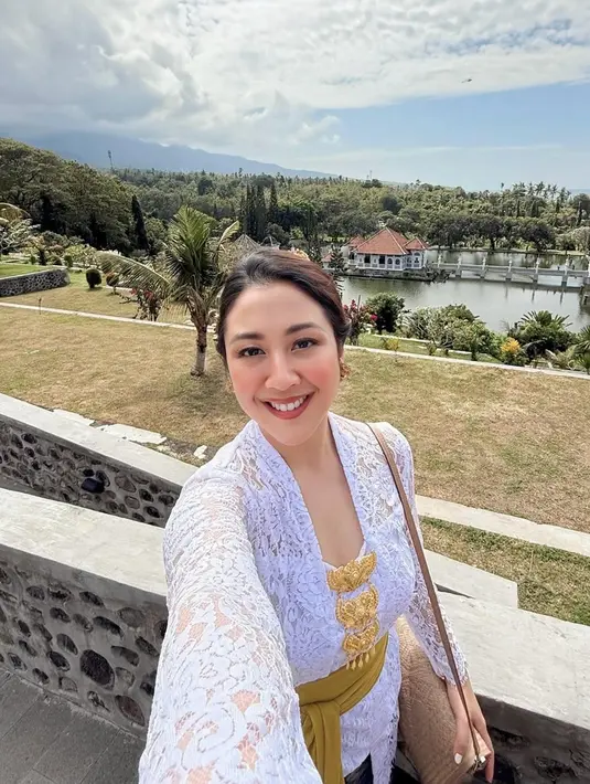 Riasan wajahnya dibuat segar dan natural, dengan fokus pada pulasan bibir nude dan alis tegas. Rambutnya disanggul sederhana nan rapi oleh @tirta_harum, memperkuat kesan klasik yang tak lekang waktu. [@sherinamunaf].