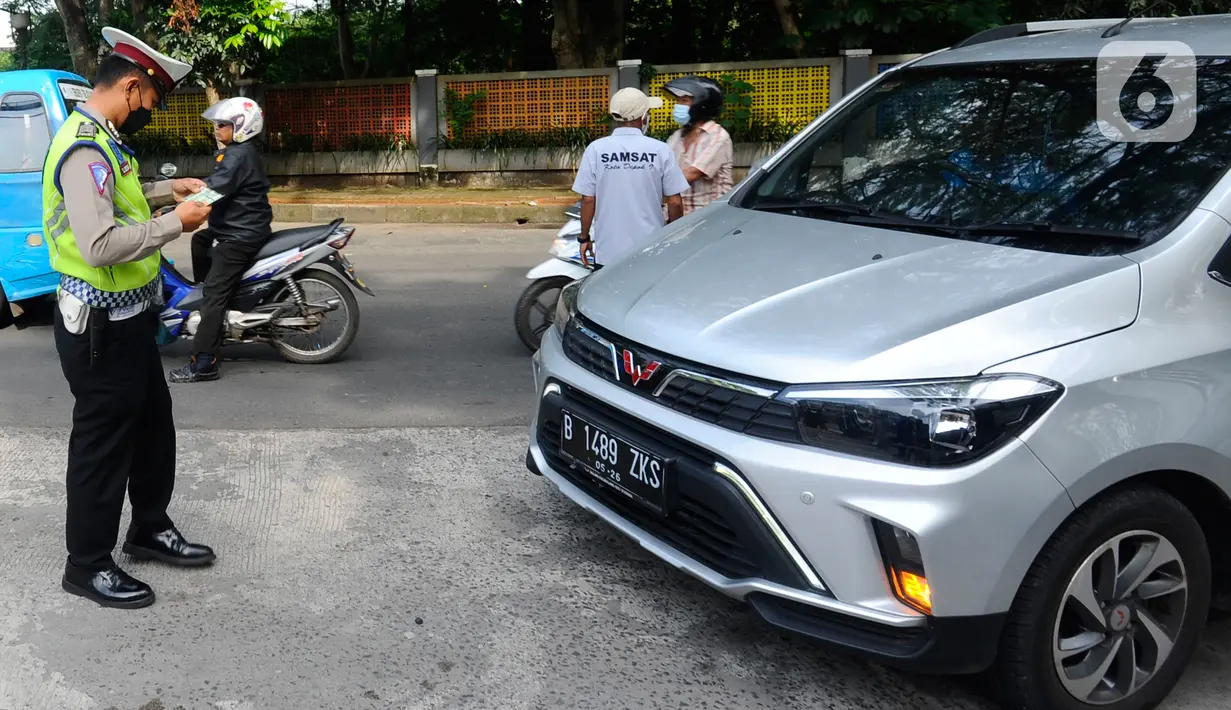 Polantas Polres Depok memeriksa surat tanda nomor kendaraan (STNK) saat Operasi Gabungan Tertib Administrasi Kendaraan Bermotor (KBM) Kendaraan Tidak Mendaftar Ulang (KTMDU) 2022 di Jembatan Panus, Depok, Kamis (9/6/2022). Ratusan kendaraan bermotor yang belum membayar pajak atau kendaraan tidak melakukan daftar ulang (KTMDU) terjaring dalam razia yang dilakukan Sistem Administrasi Manunggal Satu Atap (Samsat) Depok ini. (merdeka.com/Arie Basuki)