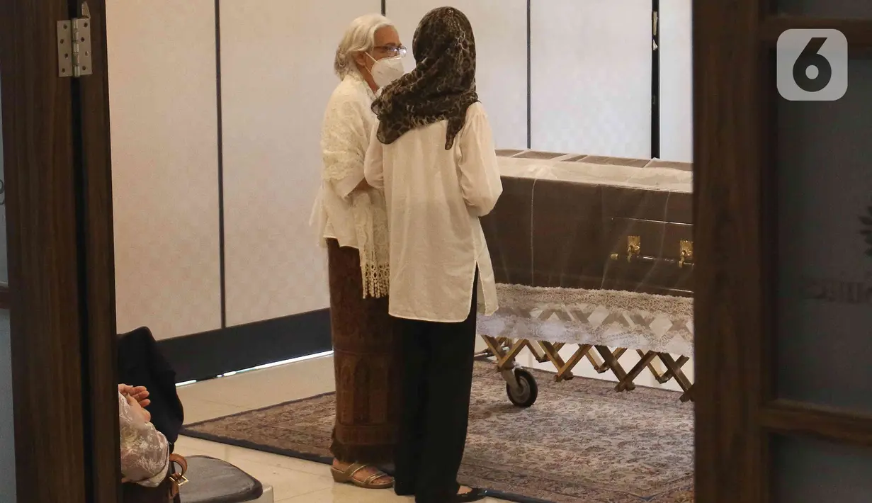 Rosmayasuto Nasution yang merupakan istri mendiang Bob Tutupoly berdiri dekat peti jenazah sang suami saat disemayamkan di Rumah Duka RS Siloam Semanggi, Jakarta Selatan, Selasa (5/7/2022). Sebelum meninggal dunia, pelantun "Widuri" tersebut sempat membutuhkan transfusi darah untuk meningkatkan hemoglobin (HB) nya. (Liputan6.com/Herman Zakharia)