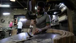 Pekerja memotong kayu untuk pembuatan alat musik Oud di sebuah rumah produksi di Damaskus, Suriah (17/7). Oud sering juga disebut Gitar Gambus yang bentuknya sepeti buah pir. (AFP Photo/Louai Beshara)