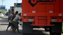 Sejumlah warga mencoba mencuri beras dari truk kargo yang tiba di pelabuhan di Puerto Cabello, Venezuela, Selasa (23/1). Penjarahan sporadis, kerusuhan pangan dan protes yang didorong oleh kelaparan telah melonjak di Venezuela. (AP Photo/Fernando Llano)