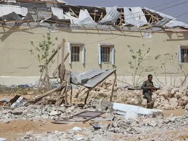 Anggota pasukan keamanan berjalan di samping bangunan yang sebagian hancur dalam serangan terhadap polisi dan pos pemeriksaan di pinggiran ibu kota Mogadishu, Somalia (16/2/2022). Serangan oleh kelompok ekstremis al-Shabab menewaskan lima orang dan melukai 16 orang. (AP Photo/Farah Abdi Warsameh)