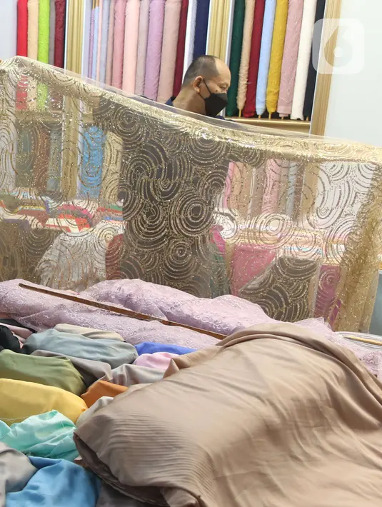 Pekerja menata bahan kain di Pasar Tanah Abang, Jakarta, Sabtu (27/11/2021). Utilisasi industri tekstil dan produk tekstil dalam negeri menunjukkan kinerja yang positif menjelang akhir 2021. Utilisasi industri itu berada di posisi 80 - 85 persen pada awal kuartal IV/2021. (Liputan6.com/Angga Yuniar)