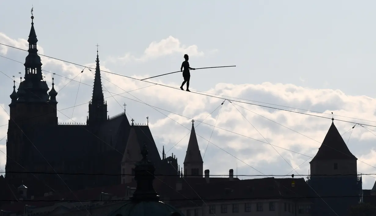Aksi akrobat perempuan, Tatiana Mosio Bongonga, berjalan meniti tali melintas di atas sungai Vltava saat pembukaan Festival Sirkus dan Teater Internasional di Praha, Ceko, Rabu (14/8/2019). (Michal Cizek / AFP)