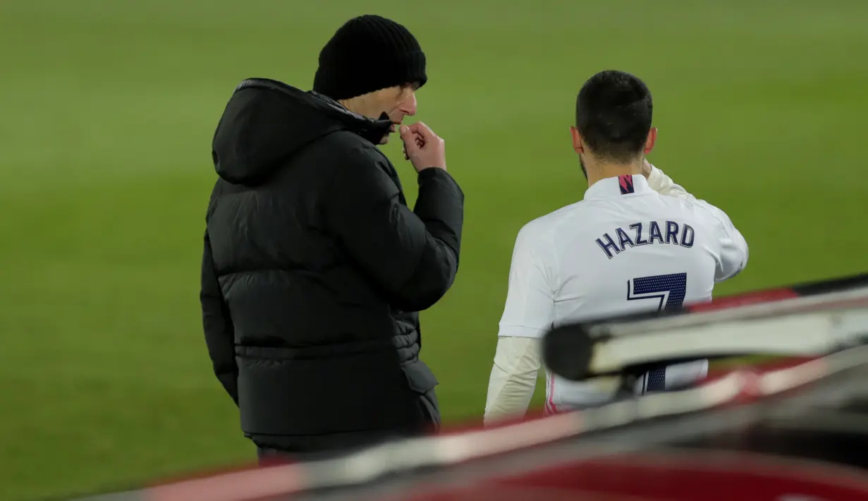 Pelatih Real Madrid, Zinedine Zidane (kiri) berbicara dengan gelandang Eden Hazard selama selama pertandingan lanjutan La Liga Spanyol di stadion Alfredo Di Stefano, Minggu (3/1/2021). (AP Photo/Manu Fernandez)