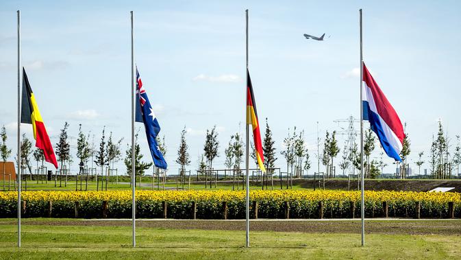 Bendera setengah tiang terpasang sebelum pembukaan taman untuk mengenang para korban pesawat MH17 di Vijhuizen, Belanda, Senin (17/7). Taman itu terdiri atas 298 pohon, mewakili penumpang dan kru yang tewas dalam pesawat naas itu (Frank van Beek/ANP/AFP)