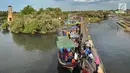 Perahu wisata melintasi kerumunan wisatawan yang berjalan di atas Jembatan Cinta di Wisata Mangrove, Tarumajaya, Bekasi, Minggu (30/12). Wisata tersebut menyajikan hutan mangrove dan makanan khas. (merdeka.com/Arie Basuki)