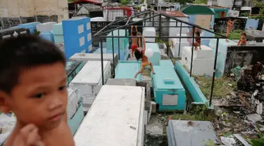 Anak-anak bermain di kuburan bergaya apartemen yang dibangun di North Cemetery, Manila, Filipina, (16/10). Kuburan ini tidak hanya menjadi tempat pemakaman orang mati, tapi juga ditinggali oleh warga yang tidak mampu membeli rumah. (Reuters/ Damir Sagolj)
