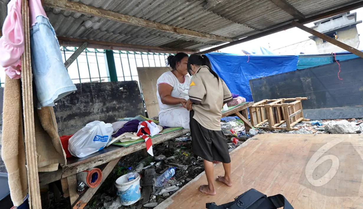 Seorang bocah terlihat ingin mengganti seragam sekolahnya di tenda darurat buatan orangtuanya di Kawasan Bongkaran, Tanah Abang, Jakarta, Rabu (21/1/2015). (Liputan6.com/Miftahul Hayat) 