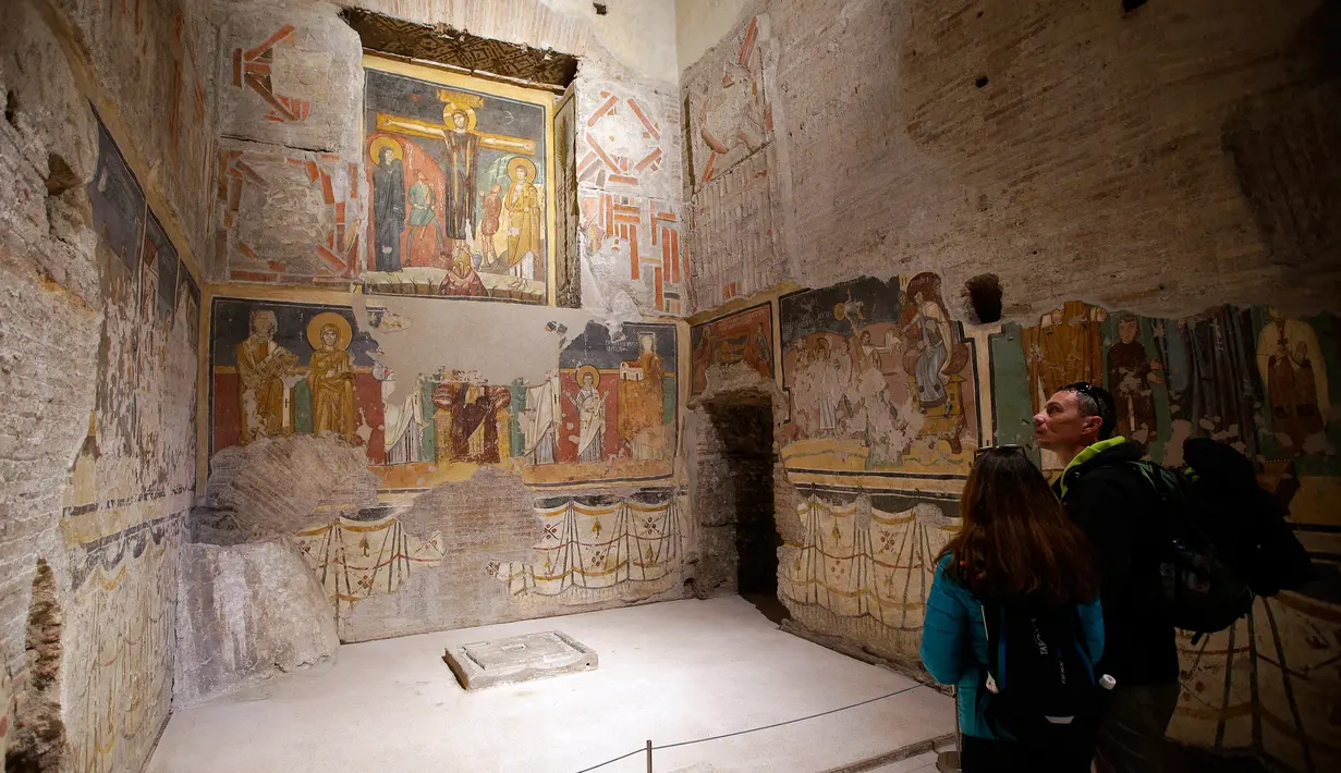 Pengunjung saat melihat lukisan dinding gereja Santa Maria Antiqua, Roma, Italia, 17 Maret 2016. Penemuan lukisan-lukisan ini telah memberikan banyak teori tentang perkembangan awal seni abad pertengahan. (REUTERS / Max Rossi)