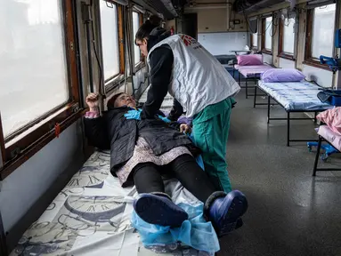 Pekerja Medecins Sans Frontieres (MSF) atau Doctors Without Border berbicara kepada seorang wanita dalam kereta medis MSF saat mengevakuasi pasien dari dekat garis depan pertempuran ke daerah yang lebih aman di stasiun kereta di Pokrovsk, Ukraina, 7 Maret 2023. MSF merupakan kereta medis khusus yang dapat membawa pasien dari bagian timur Ukraina ke rumah sakit di bagian barat. (AP Photo/Evgeniy Maloletka)