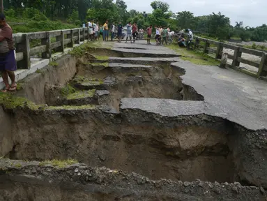 Warga India berkumpul melihat sebuah jembatan yang hancur akibat hujan deras di Desa Toribari, pinggiran Siliguri, Kamis (21/7). Hujan deras yang terus menerus turun di India dalam 48 jam terakhir menyebabkan banjir dan tanah longsor. (DIPTENDU Dutta/AFP)