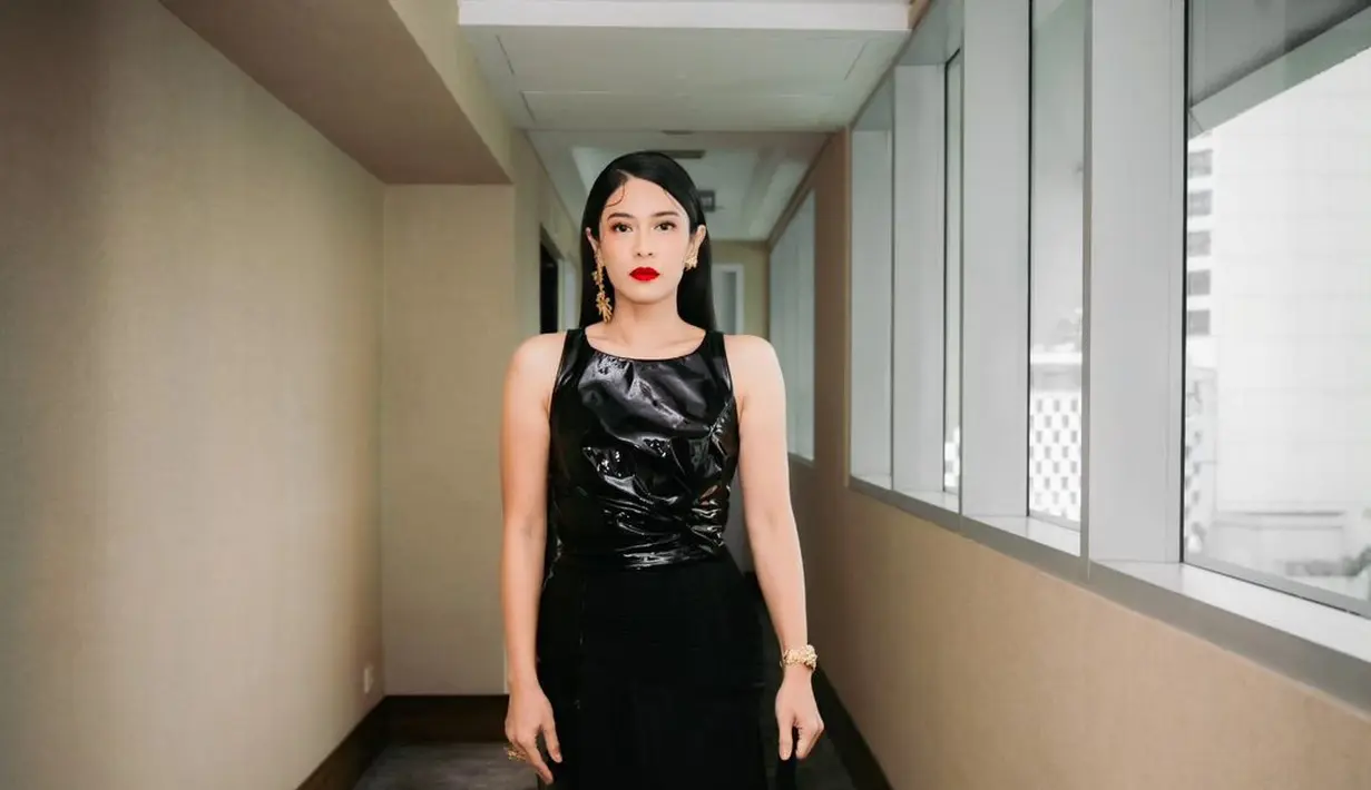 Dian Sastrowardoyo tampil bold dengan sebuah mini dress hitam tanpa lengan. Dress ini memiliki dua aksen berbeda, mini dress dari kulit dilapisi dengan rok sambungan dari bagian pinggang yang juga berwarna hitam. [Foto: Instagram/therealdisastr]