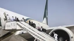 Penumpang menaiki pesawat Pakistan International Airlines (PIA) di bandara di Kabul, Afghanistan, Senin (13/9/2021). Pesawat itu tercatat sebagai penerbangan komersial internasional pertama yang mendarat sejak Taliban merebut kembali kekuasaan di Afghanistan pada Agustus lalu. (Karim SAHIB/AFP)
