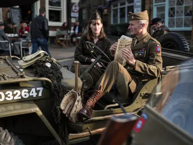 Reenactor Perang Dunia II mengenakan pakaian tentara duduk diatas Jip saat mengikuti 'Railway in Wartime Event' yang ke 25 di Pickering, Inggris (15/10). Reenactor adalah para penggiat sejarah yang mirip dengan cosplayer. (AFP Photo/Oli Scarff)