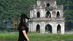 Seorang wanita dan anjingnya berjalandi sepanjang danau Hoan Kiem di Hanoi setelah kegiatan olahraga outdoor diizinkan menyusul pelonggaran pembatasan Covid-19, Selasa (28/9/2021). Sejauh ini, 94 persen dari populasi orang dewasa di Hanoi sudah menerima dosis pertama vaksin Covid. (Nhac NGUYEN/AFP)