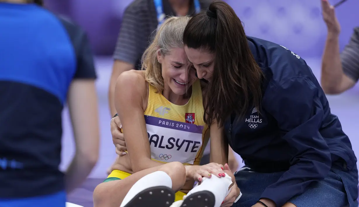 Atlet Yunani Tatiana Gusin mencoba menghibur Airine Palsyte dari Lithuania setelah ia mengalami cedera saat kualifikasi lompat tinggi putri Olimpiade Paris 2024 di Saint-Denis, Jumat, 2 Agustus 2024. (AP Photo/Bernat Armangue)
