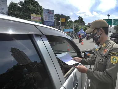 Petugas gabungan Satgas COVID-19 memeriksa surat rapid test antigen pengguna kendaraan di jalur wisata Puncak, Gadog, Bogor, Jawa Barat, Jumat (12/2/2021). Pemeriksaan dan penyekatan sebagai upaya meminimalisir penyebaran COVID-19 saat libur Imlek 2572 dan akhir pekan. (merdeka.com/Arie Basuki)