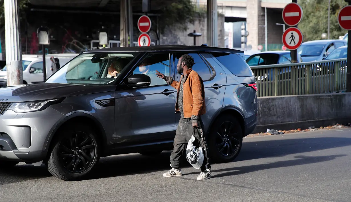 Seorang imigran mengemis kepada pengendara mobil di jalanan Kota Paris, Prancis, Rabu (6/11/2019). Pemerintah Prancis menerima 122.743 permintaan suaka tahun lalu, naik 22 persen dari tahun sebelumnya. (AP Photo/Francois Mori)