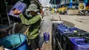 Penjual memenuhi drum atau wadah penyimpanan milik pembeli dengan air bersih yang dijualnya di Kawasan Muara Angke, Jakarta Utara, Rabu (30/8/2023). (Liputan6.com/Faizal Fanani)