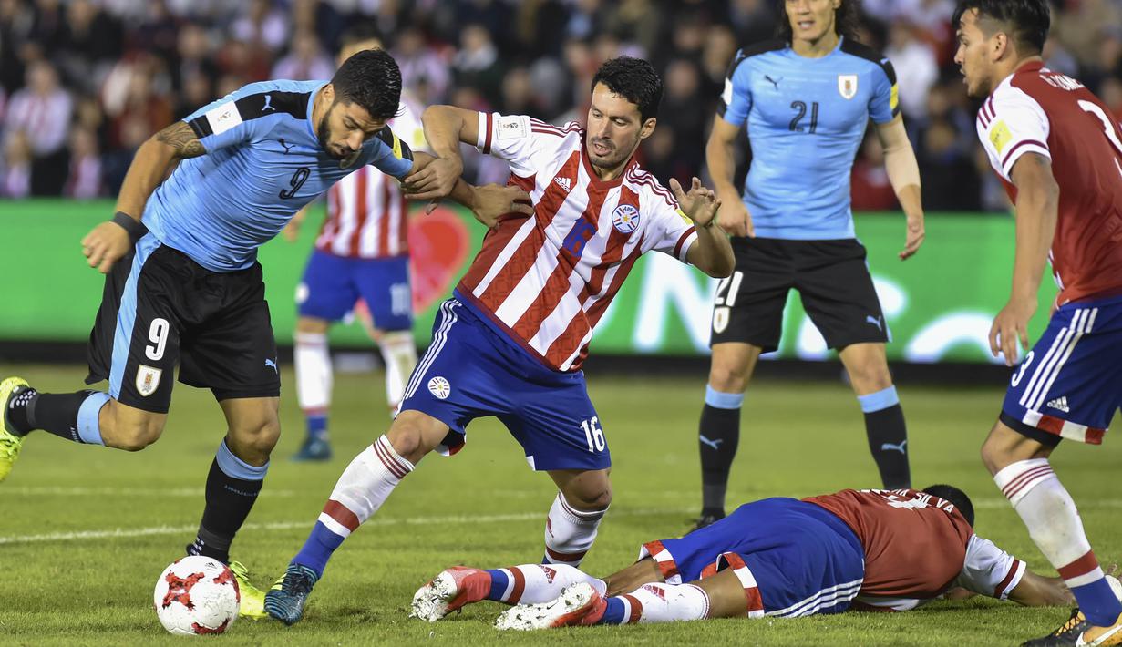 Striker Uruguay, Luis Suarez, berebut bola dengan gelandang Paraguay, Cristian Riveros, pada laga kualifikasi piala dunia 2018 di Stadion Defensores del Chaco, Rabu (6/9/2017). Uruguay menang 2-1 atas Paraguay. (AFP/Daniel Duarte)