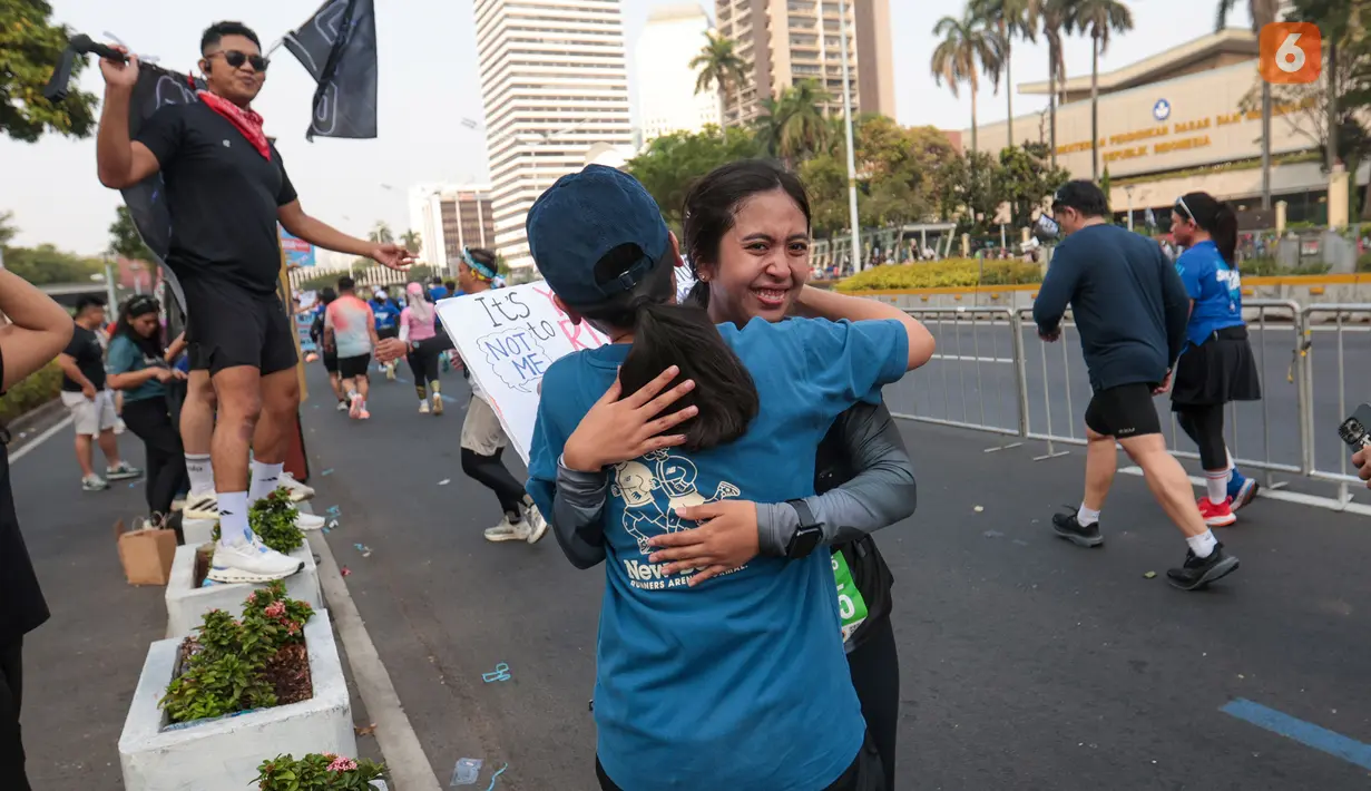 Seorang penonton memeluk temannyanya yang mengikuti Jakarta Running Festival (JRF) 2026 di kawasan Jalan Jenderal Sudirman, Jakarta, Sabtu (24/10/2026). (KLY/Budy Santoso)