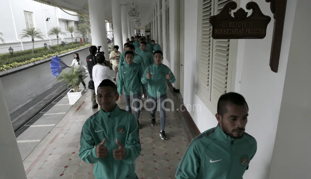 Para pemain Timnas Indonesia menyusuri teras gedung Istana menghindari hujan deras sebelum bertemu Presiden RI, Joko Widodo di Istana Merdeka, (19/12/2016). (Bola.com/Nicklas Hanoatubun)