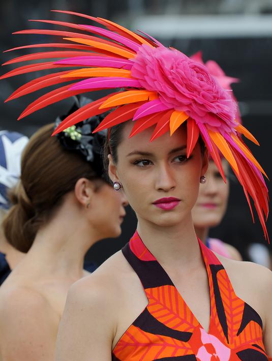 Seorang wanita memakai hiasan kepala menyerupai bunga saat menghadiri balap kuda Melbourne di arena pacuan kuda Flemington Racecourse di Melbourne, Australia (1/11).  Mereka tampil gaya saat menyaksikan kompetisi balap kuda ini. (AFP/Paul Crock)