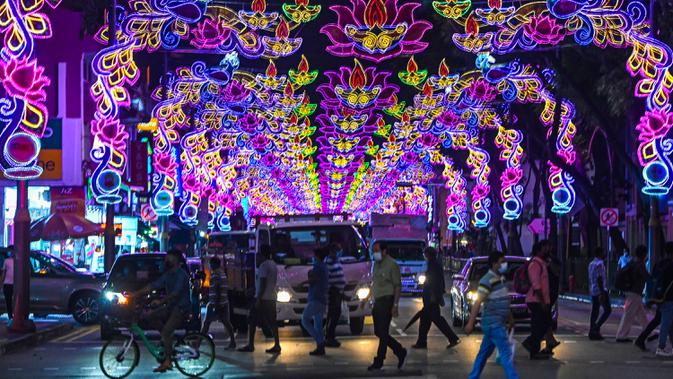 Pejalan kaki menyeberang jalan yang dihiasi dekorasi meriah menjelang Diwali, festival cahaya bagi umat Hindu, di distrik Little India di Singapura pada 23 Oktober 2020. (Photo by Roslan RAHMAN / AFP)