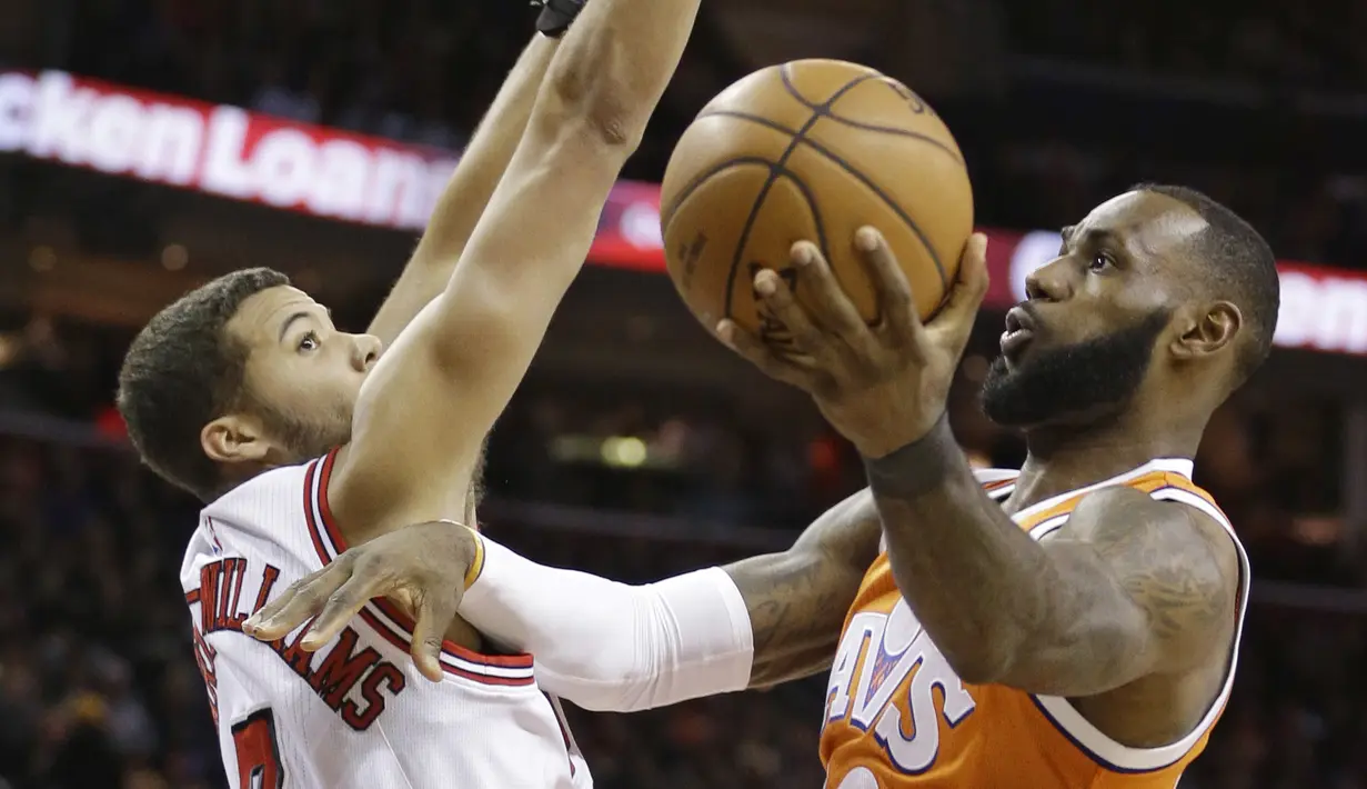 Bintang Cleveland Cavaliers, LeBron James (kanan) melakukan layup melewati hadangan pemain Chicago Bulls, Michael Carter-Williams pada aga NBA basketball game di Quicken Loans Arena, Cleveland. (AP/Tony Dejak)