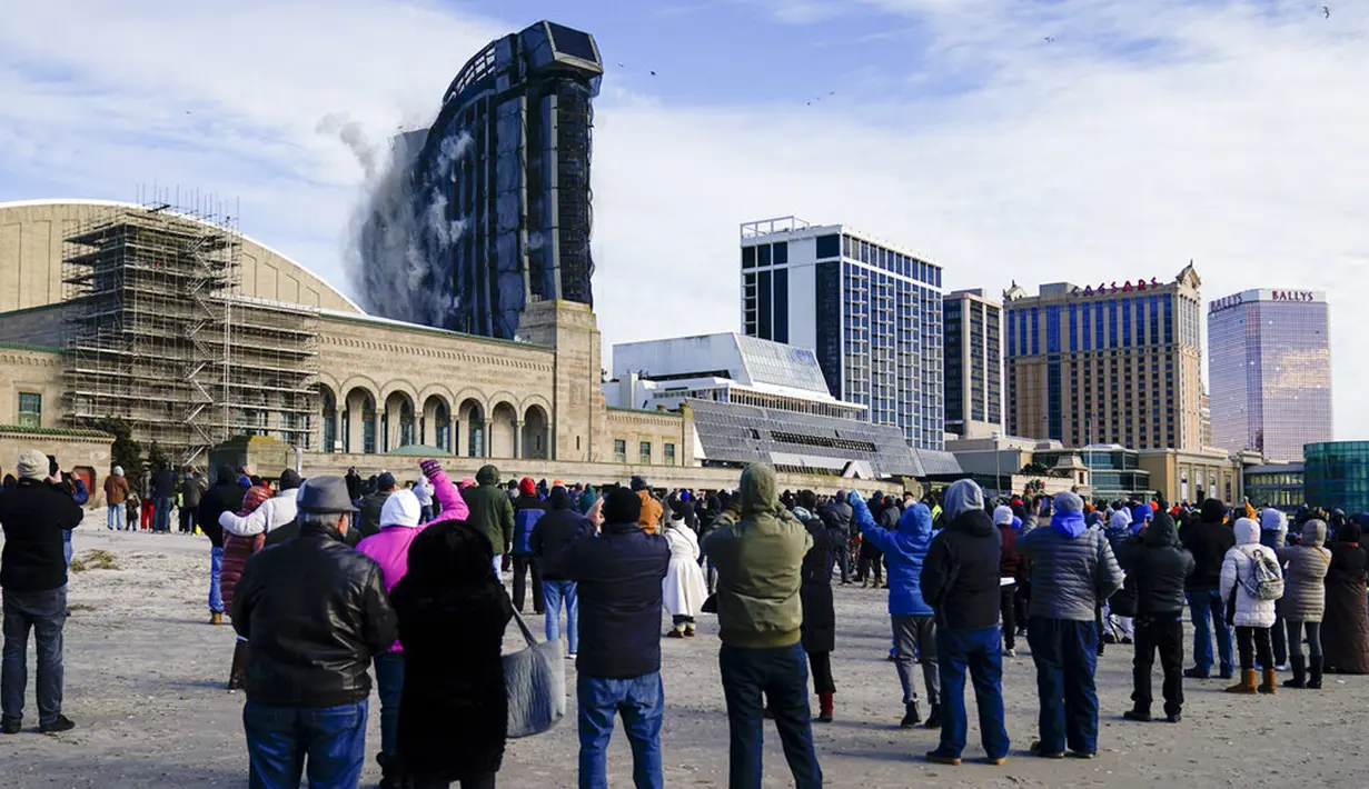 Orang-orang menyaksikan peledakan Trump Plaza Hotel and Casino di Atlantic City, New Jersey, Amerika Serikat, Rabu (17/2/2021). Pada 2014, Donald Trump sempat mengajukan gugatan untuk menghapus namanya dari fasad gedung karena bisa berdampak buruk bagi nama dan merk Trump. (AP Photo/Matt Rourke)