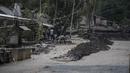 Warga membersihkan abu dan lumpur di sekitar rumah yang rusak di Dusun Kamar Kajang, Lumajang, Kamis (9/12/2021). Luapan air sungai bercampur material lahar dingin erupsi Gunung Semeru merendam puluhan rumah akibat diguyur hujan deras pada Selasa (7/12) dan Rabu (8/12) malam. (Juni Kriswanto/AFP)