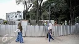 Sejumlah warga melintas di depan proyek pembangunan Taman Aspirasi Monas di seberang Istana Presiden, Jakarta, Kamis (2/6).  Taman tersebut ditargetkan akan bertepatan dengan HUT ke-489 Kota Jakarta, 22 Juni 2016 mendatang. (Liputan6.com/Faizal Fanani)