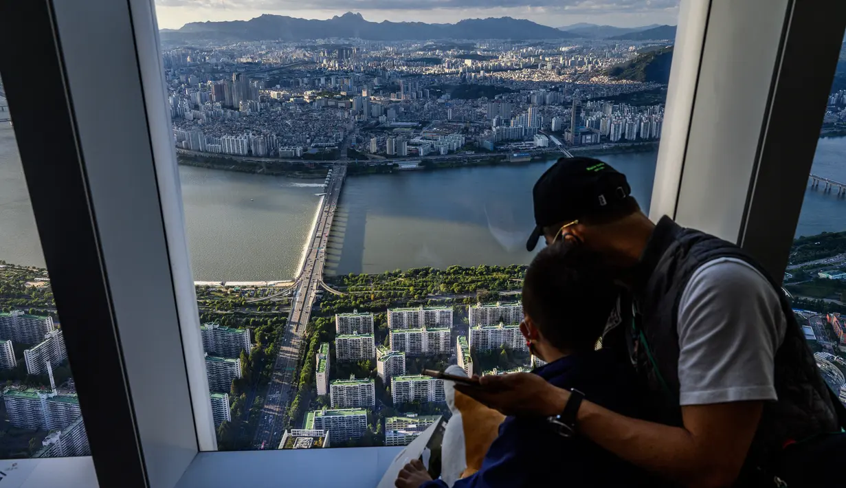 Pengunjung melihat pemandangan dari gedung pencakar langit Lotte World Tower 123 lantai di Seoul pada 22 September 2021. Lantai observatorium Lotte World Tower terbuat dari kaca, sehingga pemandangan ibu kota Korea Selatan bisa terlihat dengan jelas. (Anthony WALLACE / AFP)