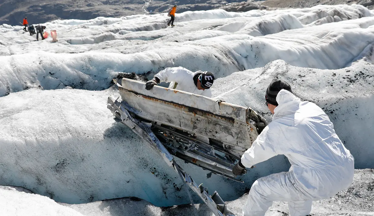 Anggota tentara Swiss mengecek bagian pesawat tempur Perang Dunia II milik AS saat ditemukan di Gauli Glacier, di Bernese Alps, Swiss (17/9). Pesawat Perang Dunia II C-53 Skytrooper Dakota tersebut jatuh tahun 1946. (Peter Klaunzer/Keystone via AP)