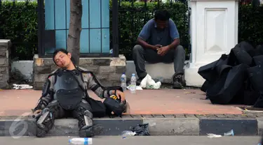 Seorang polisi tertidur di pinggir Jalan Merdeka Barat, Jakarta, Jumat (4/11). Ribuan aparat gabungan berjaga saat massa melakukan aksi di depan Istana Negara menuntut penegakan hukum kasus dugaan penistaan agama. (Liputan6.com/Helmi Fithriansyah)