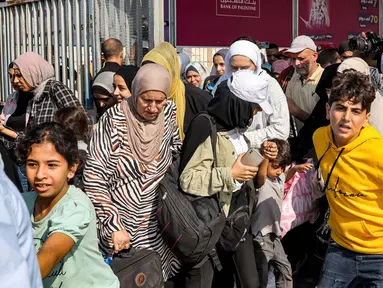 Orang-orang melewati gerbang untuk memasuki penyeberangan perbatasan Rafah ke Mesir di Jalur Gaza Selatan pada 1 November 2023. (Mohammed ABED/AFP)