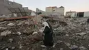 Dua wanit berjalana melewati puing-puing bangunan setelah serangan udara Israel di kota Gaza (27/10). Selain melancarkan serangan udara, Israel meluncurkan roket Iron Dome untuk menangkis rudal yang diluncurkan dari Palestina. (AFP Photo/Mahmud Hams)
