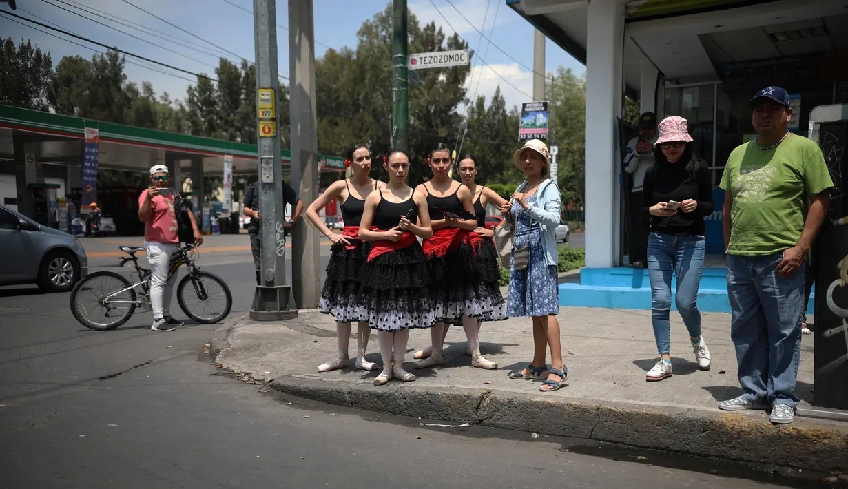 Balerina  atau penari balet menunggu di persimpangan jalan Mexico City untuk menampilkan tarian balet, 28 Juli 2018. Para balerina dari sanggar Ardentia itu melakukan pertunjukan 58 detik sesuai durasi lampu lalu lintas Kota Meksiko. (AP/Emilio Espejel)