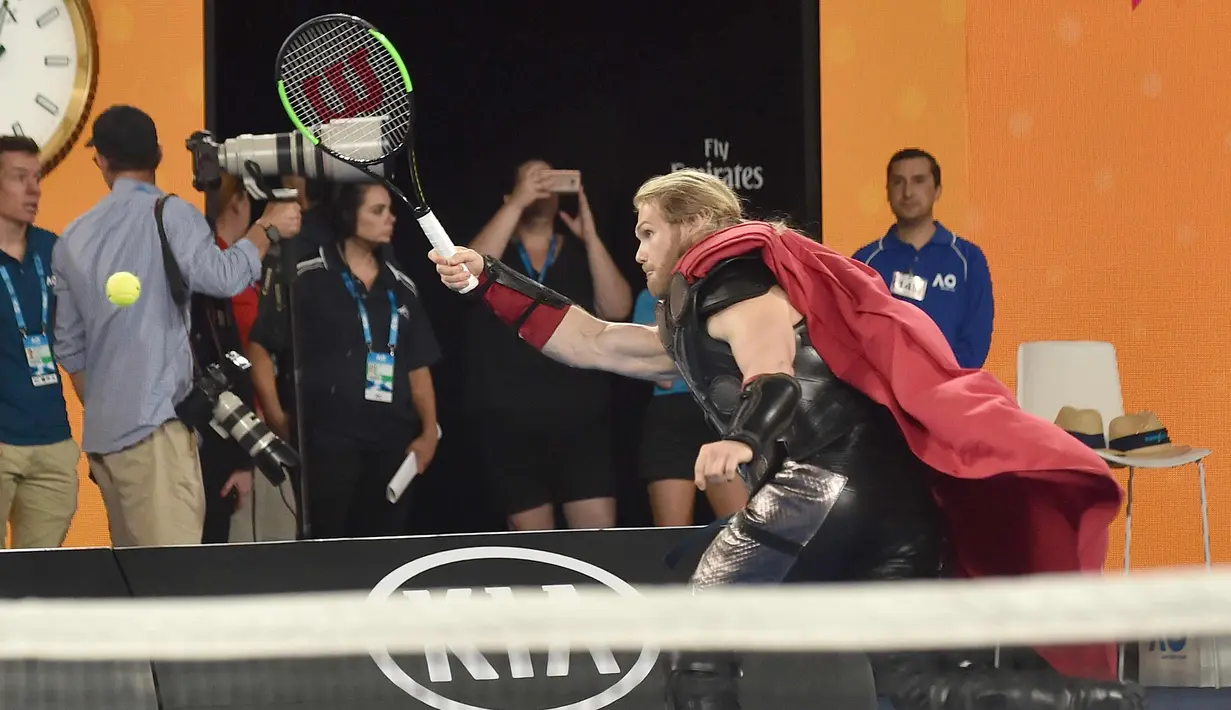 Seorang aktor berpakaian seperti karakter superhero Marvel Thor bermain tenis di Rod Laver Arena saat acara Kids Day menjelang turnamen tenis Australia Terbuka di Melbourne (13/1). (AFP Photo/Paul Crock)