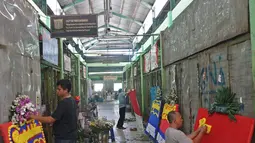 Pekerja membuat pesanan papan karangan bunga di Pasar Rawa Belong Jakarta, Selasa (25/7/2019). Selama proses revitalisasi, sekitar 600 pedagang bunga di pasar itu akan direlokasi ke Pasar Semanan Kalideres, dan Pasar Klender Duren Sawit selama proses pembangunan. (Liputan6.com/Herman Zakharia)