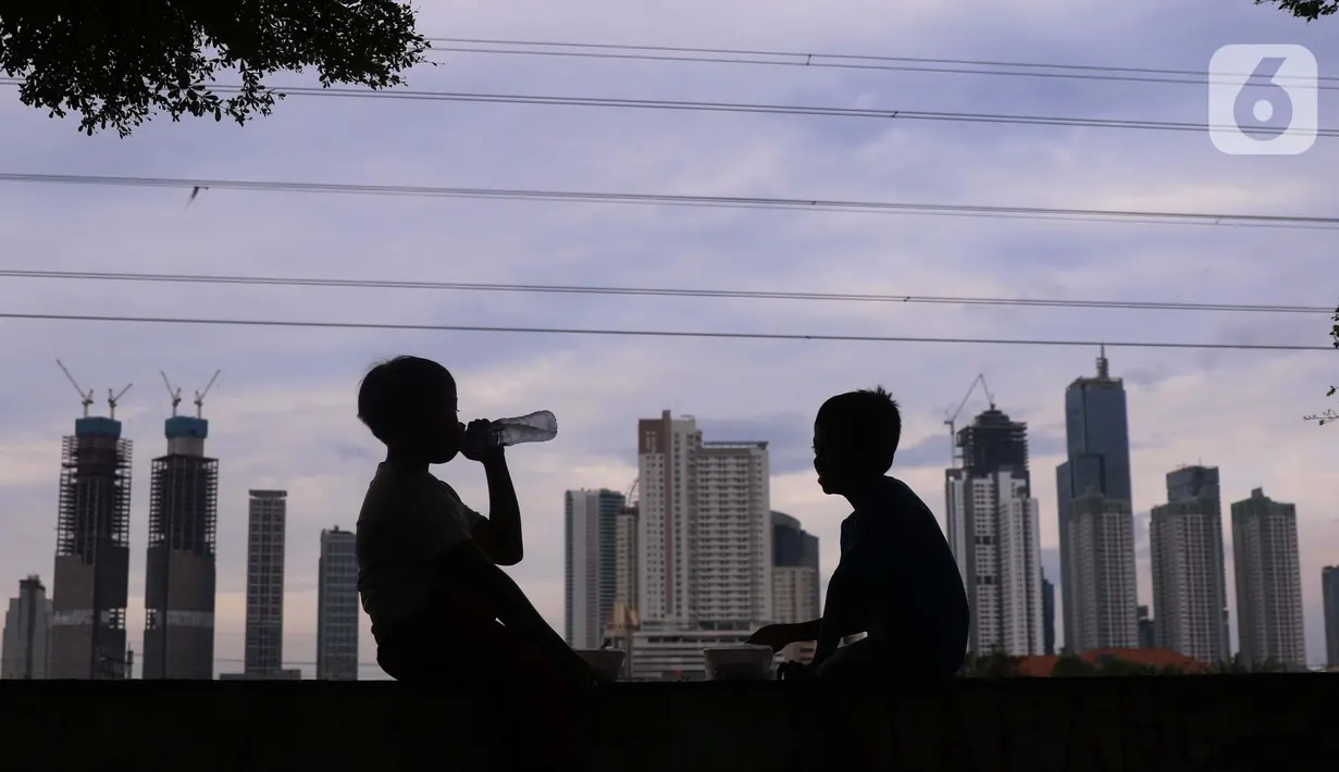 Anak-anak dengan latar gedung bertingkat menikmati minuman di Jakarta, Sabtu (19/3/2022). Bank Indonesia (BI) memperkirakan pertumbuhan ekonomi Indonesia akan meningkat lebih tinggi, pada kisaran 4,7 persen hingga 5,5 persen, dari pertumbuhan 3,69 persen pada 2021. (Liputan6.com/Angga Yuniar)