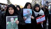 Pelayat membawa berbagai poster saat prosesi pemakaman Jenderal Qasem Soleimani dan sejumlah orang yang tewas dalam serangan Amerika Serikat di Teheran, Iran, Senin (6/1/2020). Para pelayat memegang foto Soleimani yang dianggap sebagai pahlawan oleh banyak warga Iran.  (AP Photo/Ebrahim Noroozi)