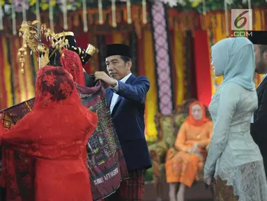 Presiden Joko Widodo dan Ibu Negara Iriana memasangkan kain ulos ke Kahiyang Ayu dan Bobby Nasution saat pesta adat di Bukit Hijau Regency Taman Setia Budi (BHR Tasbi), Medan, Sabtu (25/11). (Liputan6.com/Pool/Media Center)